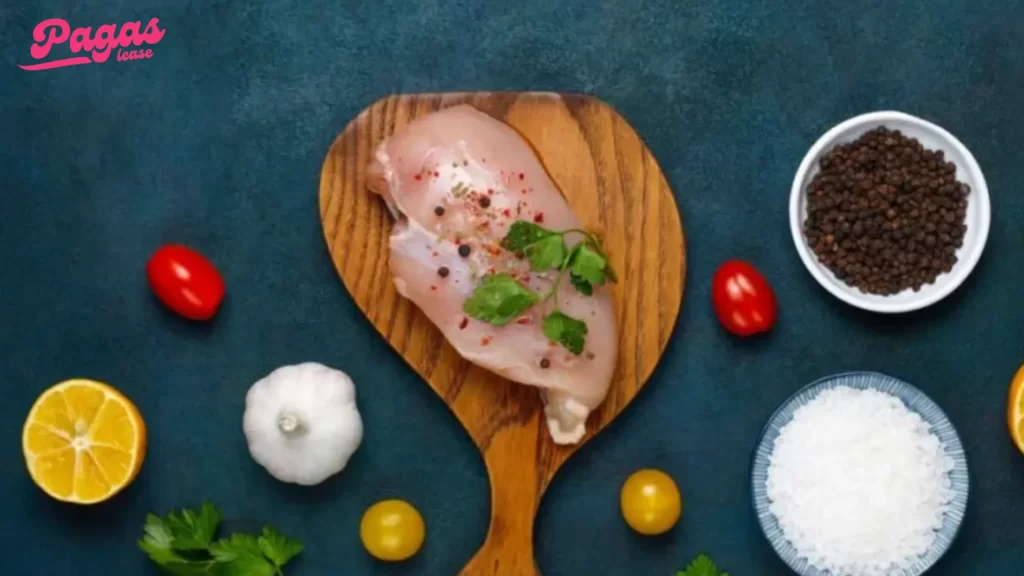 Chicken breast surrounded by seasonings and vegetables, ready for preparation.